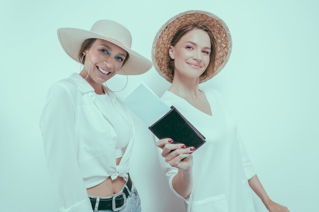 Ritratto di due donne sorridenti con passaporti e carte d'imbarco nelle loro mani. Concetto di viaggio. Tecnica mista