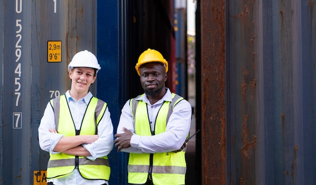 Ritratto di due lavoratori in piedi con le braccia incrociate davanti al container
