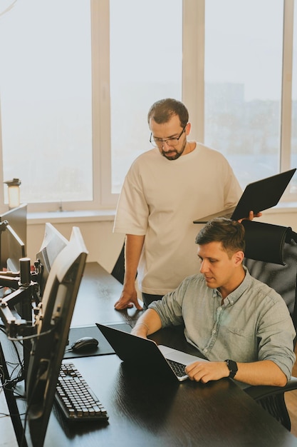 Ritratto di due programmatori maschi professionisti che lavorano su computer in diversi uffici Moderne tecnologie IT sviluppo di applicazioni di programmi di intelligenza artificiale e concetto di videogiochi