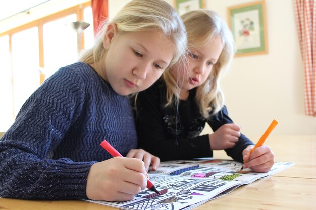 Ritratto di due ragazze bionde che colorano con i marcatori