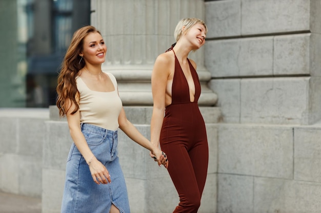 Ritratto di due ragazze che ridono, amici, viaggiatori, turisti per la strada della città.