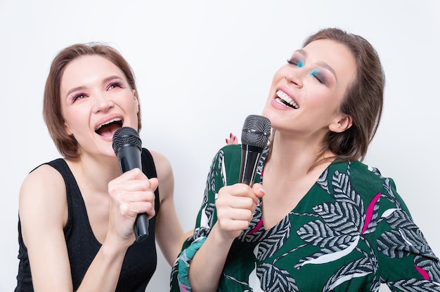 Ritratto di due ragazze con microfoni in mano. Concetto di karaoke. Tecnica mista