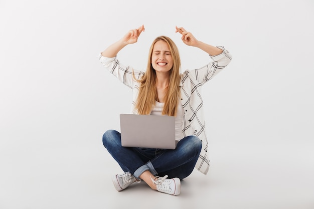 Ritratto di eccitata giovane donna casual utilizzando il computer portatile