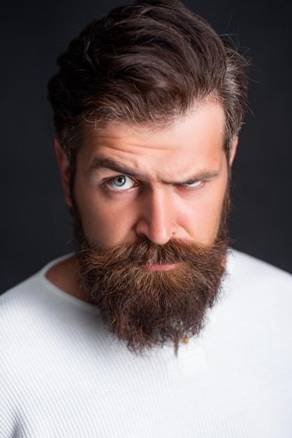 Ritratto di elegante bel giovane con la barba in piedi sul muro nero.