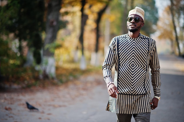 Ritratto di elegante uomo afroamericano nero con cappello e occhiali da sole su sfondo autunnale soleggiato Persone ricche in africa in abito tradizionale