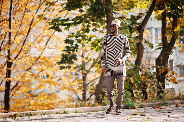 Ritratto di elegante uomo afroamericano nero con cappello e occhiali da sole su sfondo autunnale soleggiato