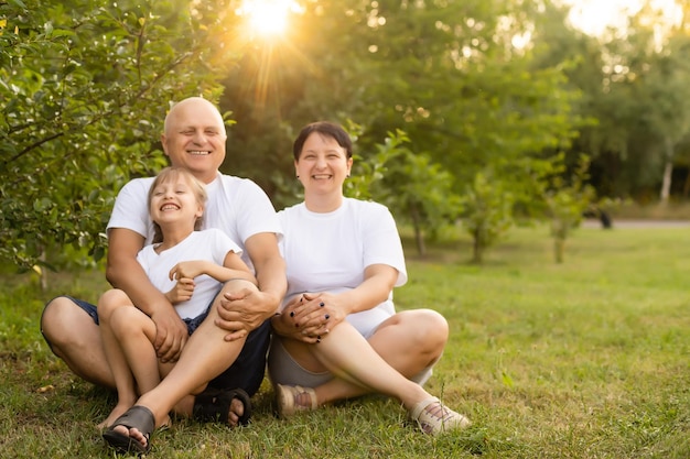 Ritratto di famiglia allargata allegra seduta nel parco