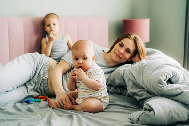 Ritratto di famiglia della mamma con i bambini nella camera da letto sul letto