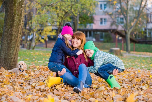 Ritratto di famiglia di donna e bambini si siedono al fogliame