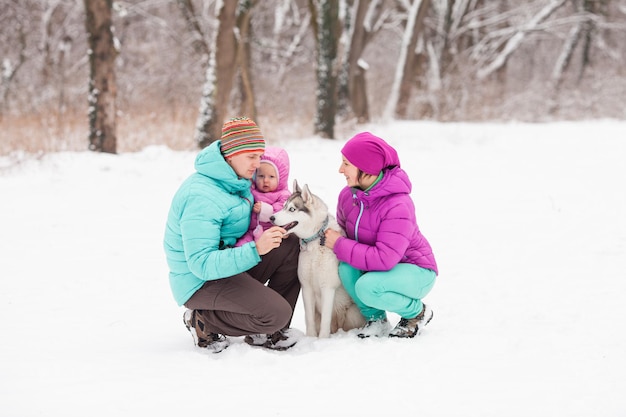 Ritratto di famiglia e il loro animale domestico - cane husky, seduto sulla neve in inverno day