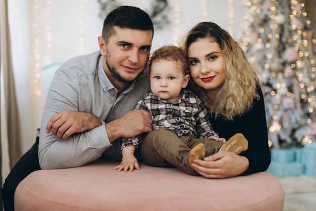 Ritratto di famiglia felice di padre madre e piccolo figlio riccio che festeggiano il Natale insieme a casa Concetto di Capodanno