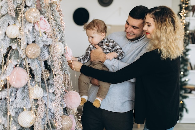 Ritratto di famiglia felice di padre madre e piccolo figlio riccio che festeggiano il Natale insieme a casa Concetto di Capodanno