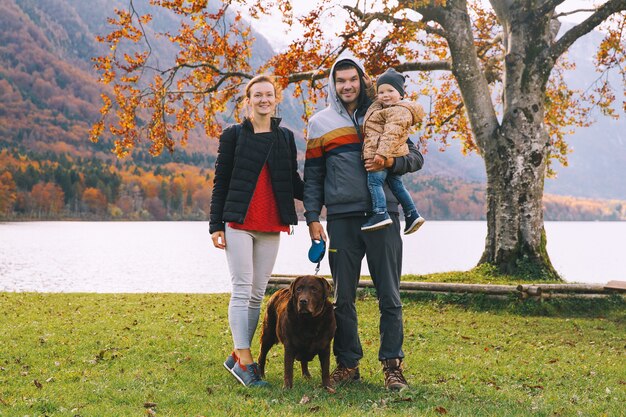 Ritratto di famiglia felice madre padre figlio e cane all'aperto autunno sul lago di Bohinj Europa