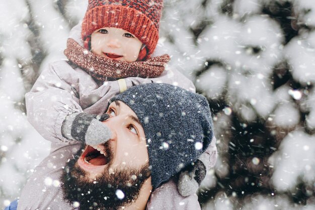 Ritratto di famiglia felice Padre e figlio bambino in vacanza invernale nei pressi di albero di Natale Padre dando figlio cavalcare indietro nel parco Felice famiglia gioiosa