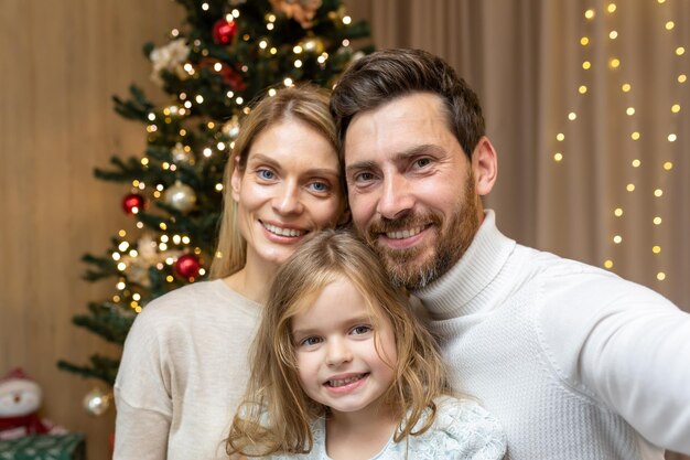 Ritratto di famiglia felice su Natale famiglia uomo donna e figlia guardando la fotocamera e sorridente