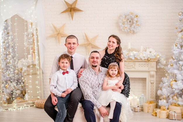 Ritratto di famiglia in studio decorato per il nuovo anno. Serata di Natale in famiglia. famiglia per riunirsi abbracciando e sorridendo. soggiorno decorato con camino e albero di Natale