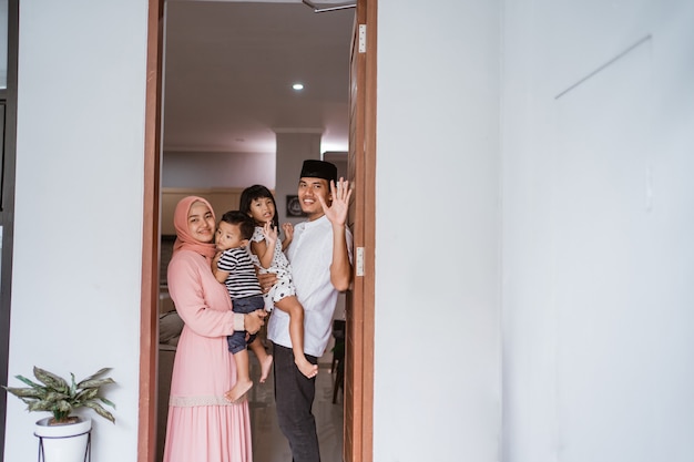 Ritratto di famiglia musulmana in piedi davanti alla loro casa porta d'ingresso che accoglie gli ospiti a casa durante la celebrazione di eid mubarak