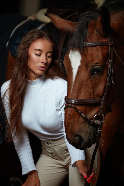 Ritratto di fantino femmina sorridente in piedi a cavallo nella stalla