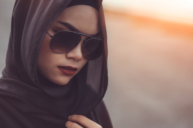 Ritratto di Fashi di giovane bella donna musulmana con l'hijab nero e occhiali da sole. Stile vintage