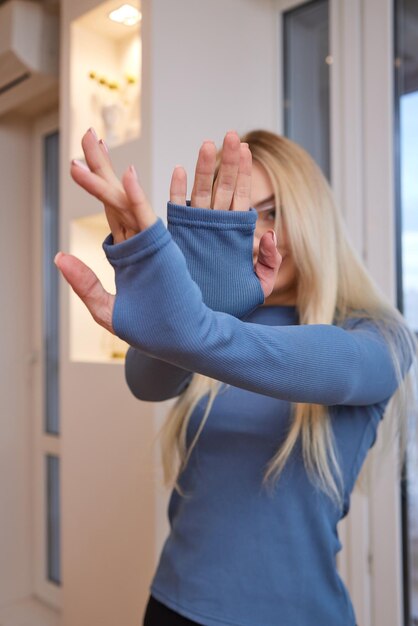 Ritratto di felice affascinante ragazza bionda allegra con gli occhiali sorride guardando felice e felice vivace con trucco naturale abbronzato vestito con una maglietta a maniche lunghe azzurra casual