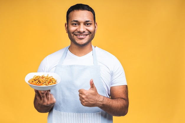 Ritratto di felice chef afroamericano indiano nero uomo cucinare la pasta. Cucina, professione, alta cucina, cibo e concetto di persone isolato su sfondo giallo.