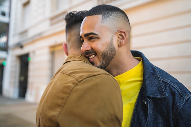 Ritratto di felice coppia gay di trascorrere del tempo insieme e abbracciando in strada