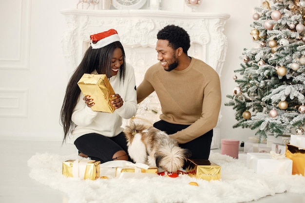 Ritratto di felice coppia nera in possesso di regali e seduta vicino all'albero di Natale