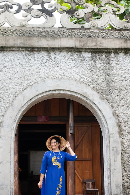 Ritratto di felice donna caucasica in abito Ao Dai visita il tempio all'aperto