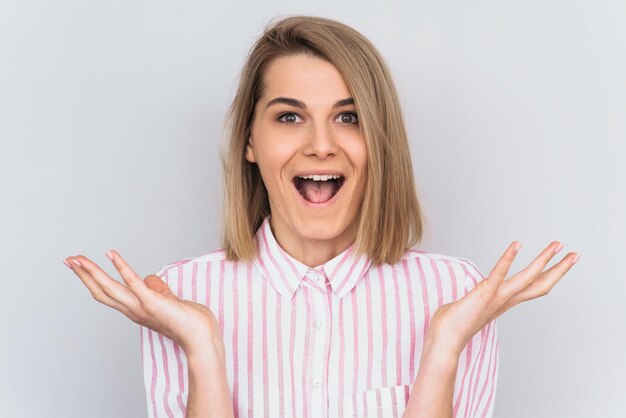 Ritratto di felice donna felicissima indossa una camicia a righe rosa gesti con eccitazione isolato su bianco studio bakground Modello femminile gioisce del successo sul lavoro Concetto di emozione della gente