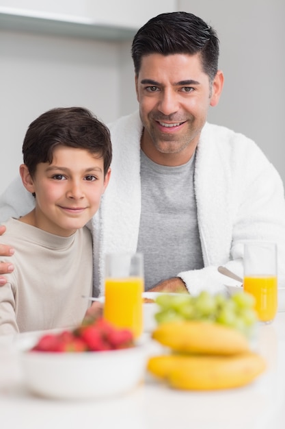 Ritratto di felice figlio con padre facendo colazione