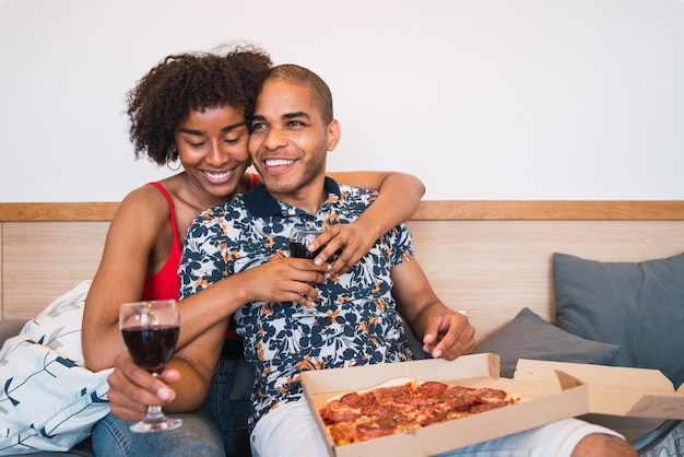 Ritratto di felice giovane coppia latina cenando insieme e bevendo vino a casa loro. Stile di vita e concetto di relazione.