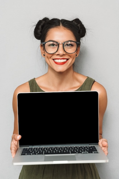 Ritratto di felice giovane donna isolata, mostrando laptop schermo vuoto