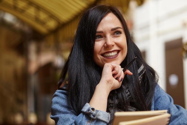 Ritratto di felice imprenditrice casual in giacca seduta al suo posto nella caffetteria