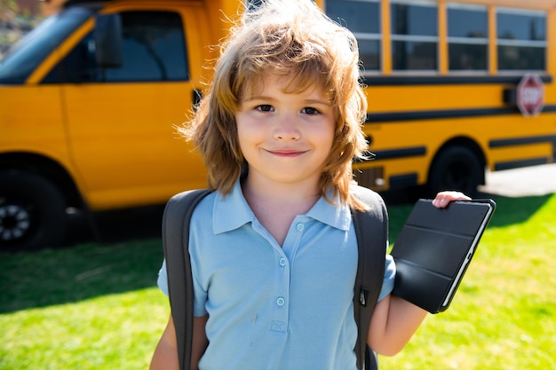 Ritratto di felice piccolo allievo scolaro all'aperto sullo scuolabus