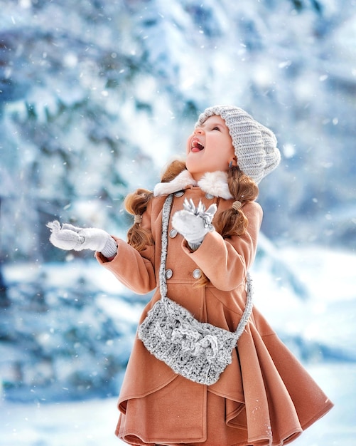 Ritratto di felice ragazza allegra in inverno nel parco cattura i fiocchi di neve con la lingua della bocca godendosi l'inverno nel parco