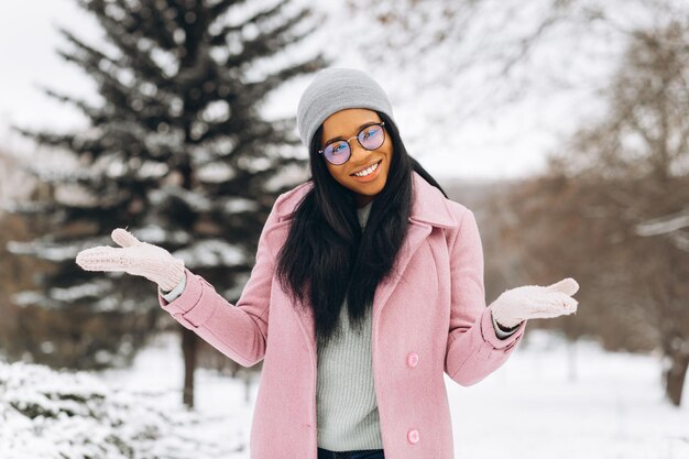 Ritratto di felice ragazza positiva Giovane donna afroamericana in occhiali e guanti nel parco invernale