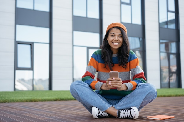 Ritratto di felice studente emotivo studiando, tenendo lo smartphone, concetto di formazione online