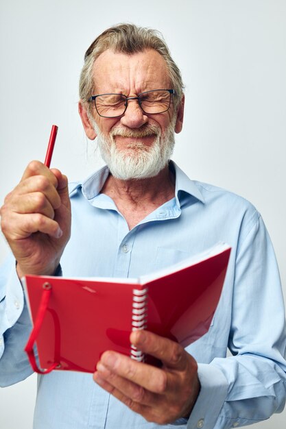 Ritratto di felice uomo anziano rosso blocco note scrittura sfondo chiaro