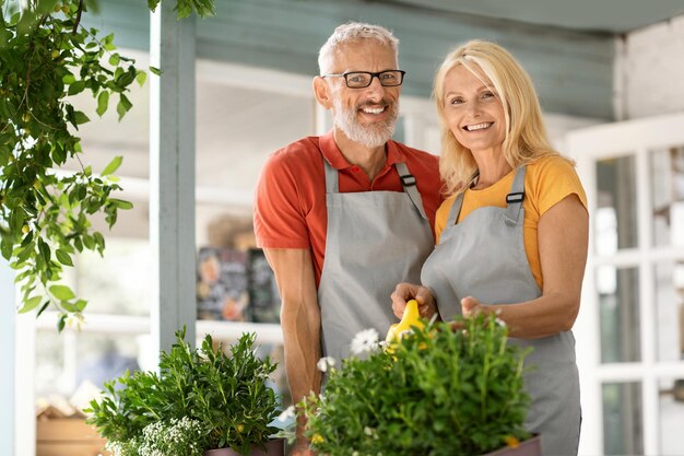 Ritratto di felice uomo maturo e donna che fanno giardinaggio insieme in una casa di campagna