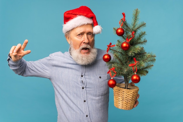 Ritratto di felici emozioni pazze babbo natale eccitato guardando la fotocamera e tiene piccoli tre di natale