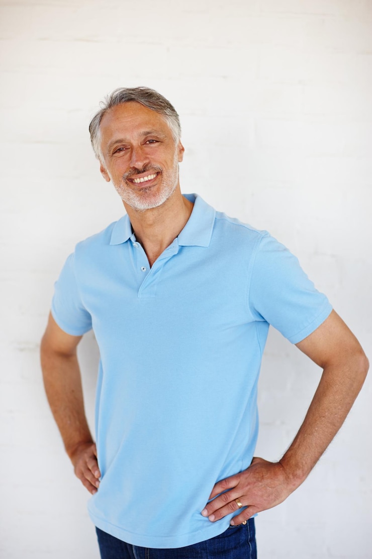 Foto ritratto di fiducia e sorriso di un uomo anziano su un muro di mattoni per la moda isolato su uno sfondo bianco in svizzera testa persona matura e felice in abiti casuali camicia e positiva per lo stile