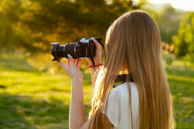 Ritratto di fotografa professionista nel parco che fotografa su una macchina fotografica. servizio fotografico sessione fotografica nella vista posteriore della città.