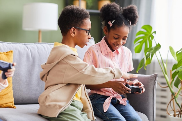 Ritratto di fratello e sorella afroamericani che giocano insieme ai videogiochi a casa