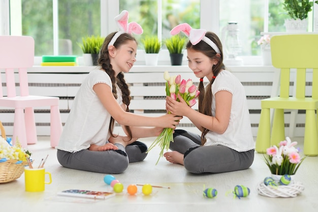 Ritratto di gemelli carini che indossano orecchie di coniglio che decorano le uova di Pasqua