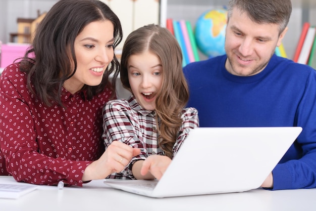 Ritratto di genitori e figlia che utilizzano laptop in camera