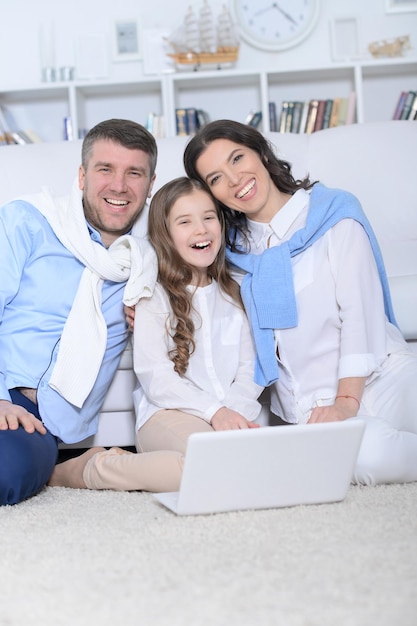 Ritratto di genitori e figlia che utilizzano laptop in camera