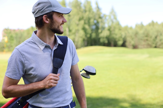 Ritratto di giocatore di golf maschio che trasportano la sacca da golf mentre si cammina da erba verde del golf club.