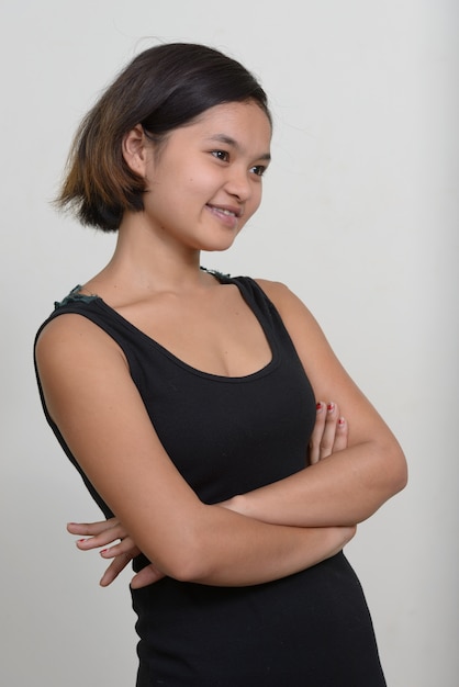 Ritratto di giovane adolescente asiatica con i capelli corti contro il muro bianco