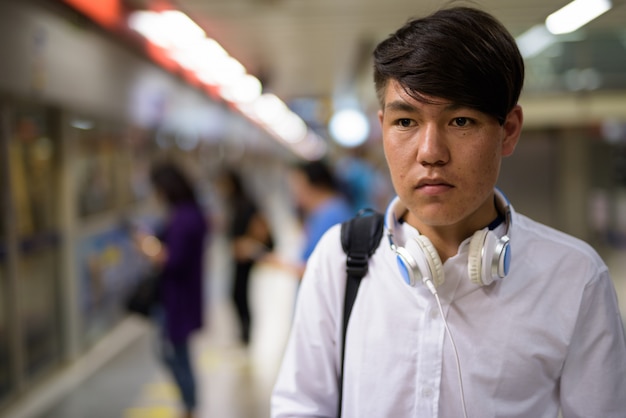 Ritratto di giovane adolescente asiatico che aspetta il treno alla stazione della metropolitana di Bangkok, Tailandia