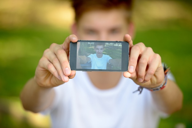 Ritratto di giovane adolescente bello che si distende al parco all'aperto